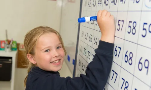 child writing on white board - CVP