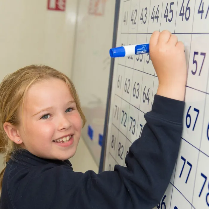 child writing on white board - CVP