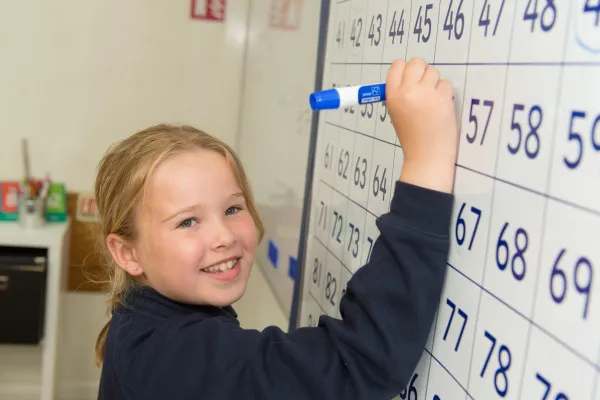 child writing on white board - CVP